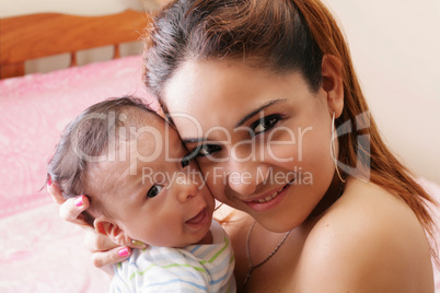 Portrait of a hispanic happy young mother holding a baby