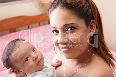 beautiful hispanic young mother is holding her newborn baby