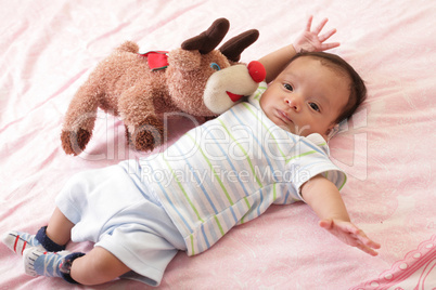 hispanic baby with teddy bear laying on bed