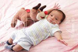 hispanic baby with teddy bear laying on bed
