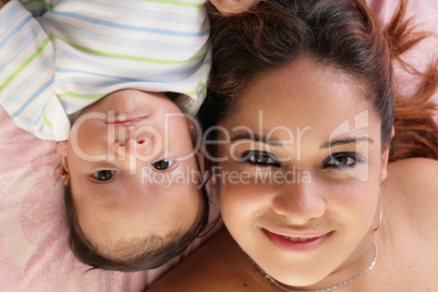 Portrait of a beautiful hispanic happy mother with baby lying do