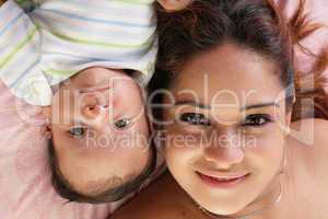 Portrait of a beautiful hispanic happy mother with baby lying do