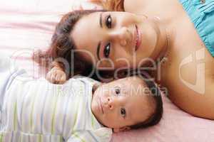 Portrait of happy young attractive hispanic mother lying with he