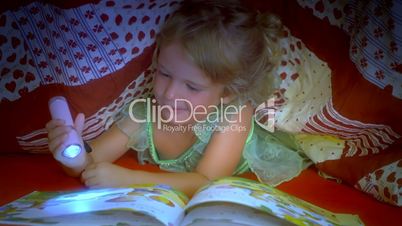 Little girl reading book under covers sleeping