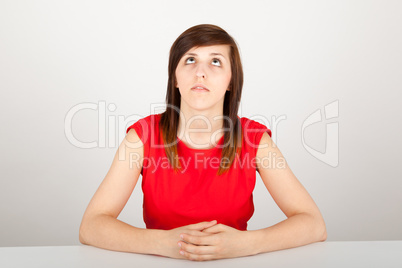 Die junge Frau sitzt gelangweilt an einem Tisch