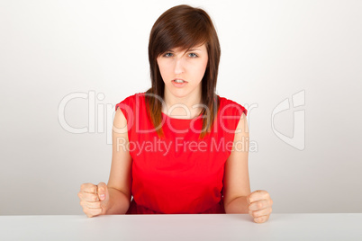 Die junge Frau sitzt wütend an einem Tisch