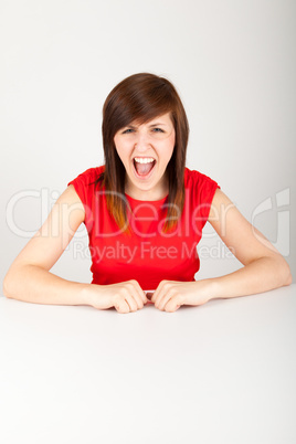 Die junge Frau sitzt zornig an einem Tisch