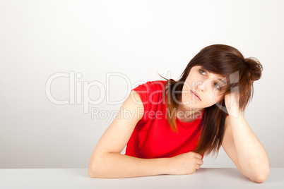 Die junge Frau sitzt müde an einem Tisch