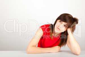 Die junge Frau sitzt müde an einem Tisch