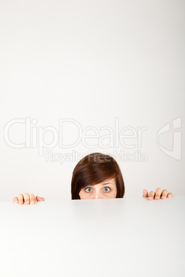 Die junge Frau versteckt sich ängstlich hinter einem Tisch
