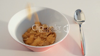 cornflakes being poured in a bowl