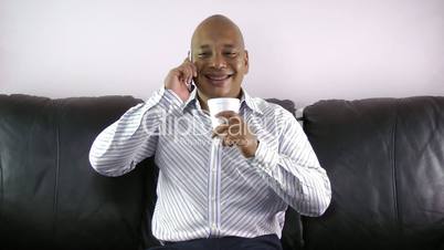 African man drinking while talking on phone