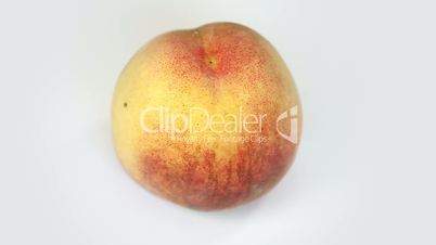 Ripe  peach fruit rotating on white background