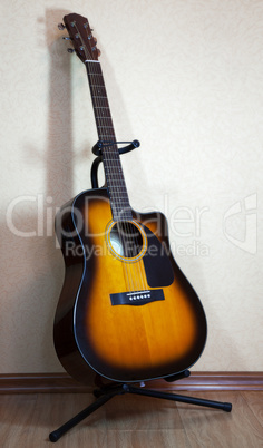 six-string acoustic guitar on a stand