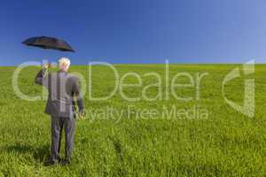 Businessman In A Green Field With An Umbrella