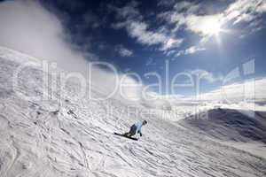 snowboarder on off-piste ski slope and blue sky with sun