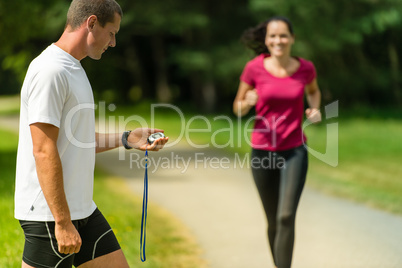 Portrait of male coach timing runner outdoors