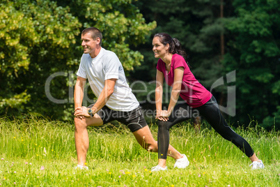Female and male runner stretching outdoors