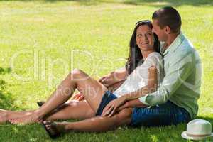 Hugging couple sitting in grass outdoors