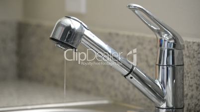 Close up of man turning off dripping kitchen sink faucet