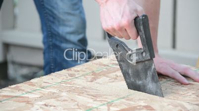 Angled view of man sawing wood plank