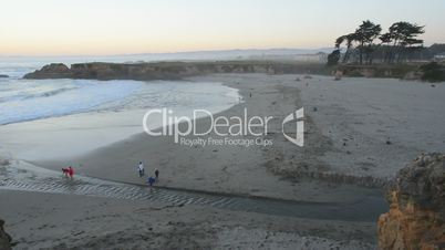 Visitors walk along the beach at sunset