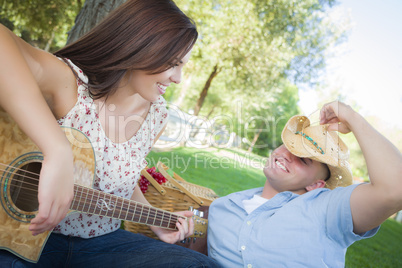 Mixed Race Couple with Guitar and Cowboy Hat in Park