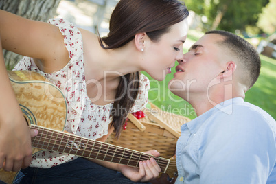 Mixed Race Couple with Guitar Kissing in the Park