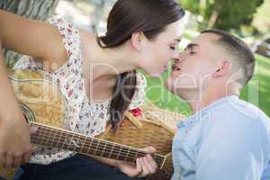 Mixed Race Couple with Guitar Kissing in the Park