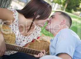 Mixed Race Couple with Guitar Kissing in the Park