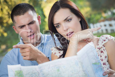 Lost and Confused Mixed Race Couple Looking Over Map Outside