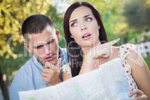 Lost and Confused Mixed Race Couple Looking Over Map Outside
