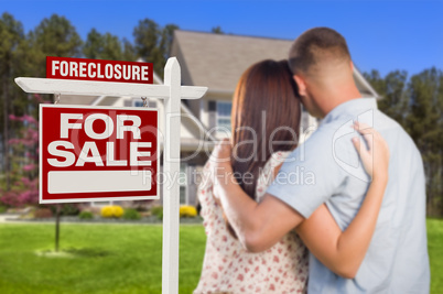 Military Couple Standing in Front of Foreclosure Sign and House