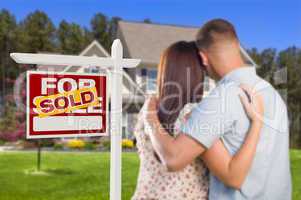 Sold For Sale Sign with Military Couple Looking at House