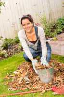 Happy woman filling bucket leaves fall gardening