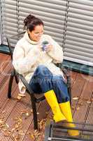 Cheerful woman drinking tea autumn rubber boots