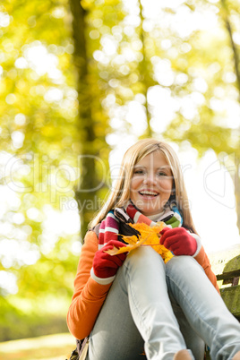 Happy blonde girl teen sitting forest fall