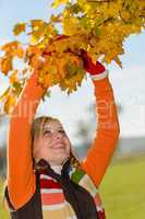 Smiling girl picking dry leaves autumn tree