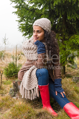 Posing autumn woman sitting in pinewood forest