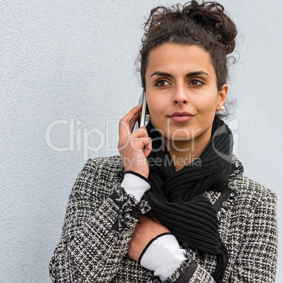 Woman in coat holding phone paying attention