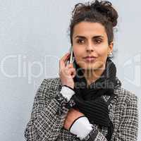 Woman in coat holding phone paying attention