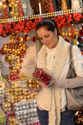 Young woman buying christmas balls in shop