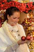 Smiling woman holding Christmas balls at shop