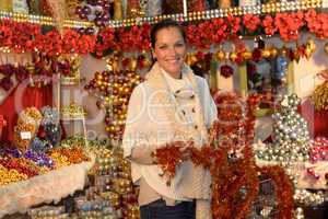 Cheerful woman buying Christmas tinsel garland