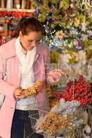 Woman putting Xmas decorations to shopping basket