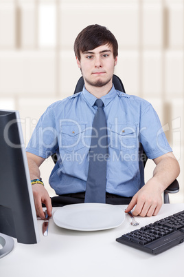 Young businessman sitting in front of empty plate in the office