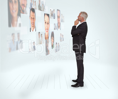 Thoughtful businessman looking at a wall covered by profile pict