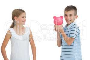 Smiling young boy holding piggy bank