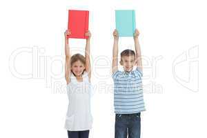 Happy brother and sister holding their notebooks above their hea