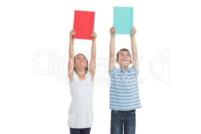Smiling brother and sister holding their notebooks above their h